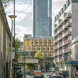 Pedestrians and vehicles travelling down a road in Manchester city centre