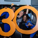 People smiling and holding a 30 sign 