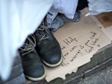 A homeless person's shoes and a sign on the floor which says 'Please help if you can. No worries if you can't. God bless. x'
