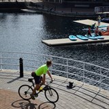 A cyclist looking over at paddle boarders at Salford Quays