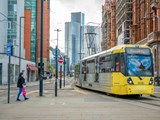 Person walking and tram in motion in Manchester city centre